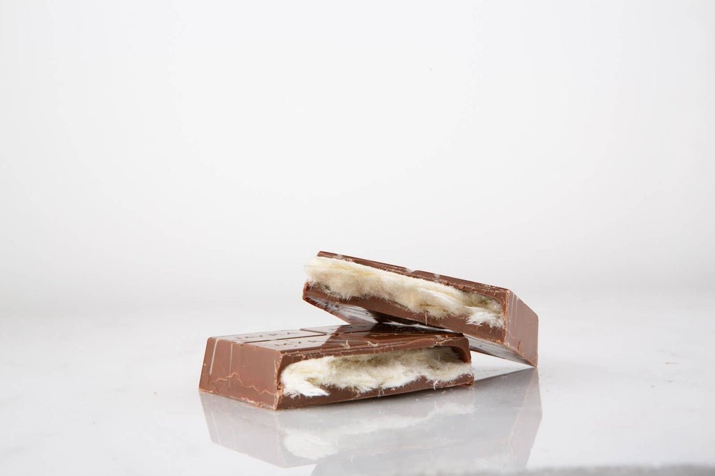 Candy Shack milk chocolate bar filled with fluffy vanilla cotton candy, split to show the airy interior texture.